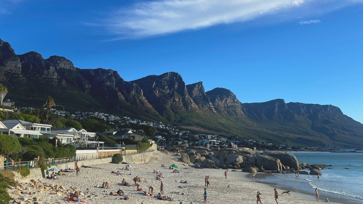 A cinematic wide shot of the rugged Cape Town coastline at sunset.