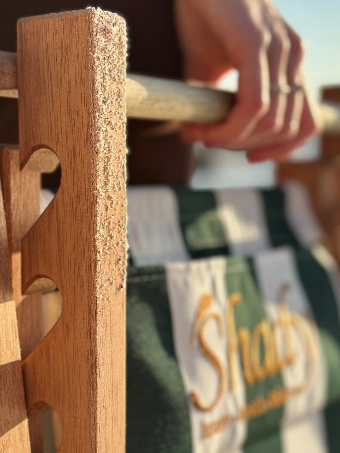 A hand resting on the crafted wooden armrest of a Shady.